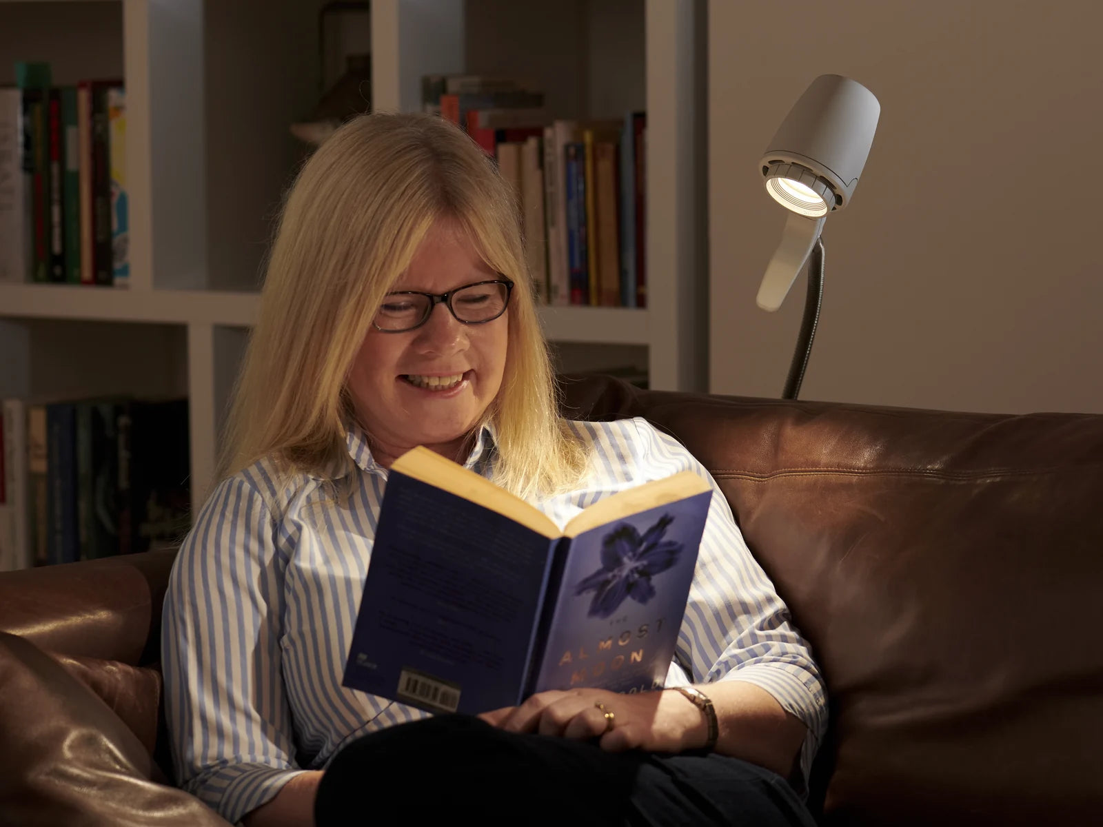 A woman smiling over her book by an HD Original Floor Light in Heritage White