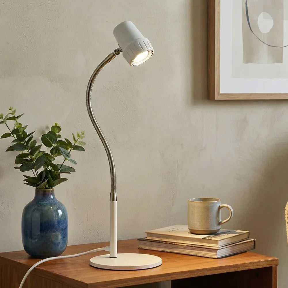 An HD Essential Table Light in Heritage White on a wooden side table, beside a vase and a mug