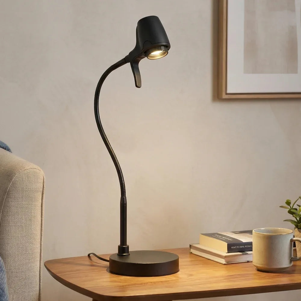 An HD Pro Table Light in Black on a side table beside books and a mug