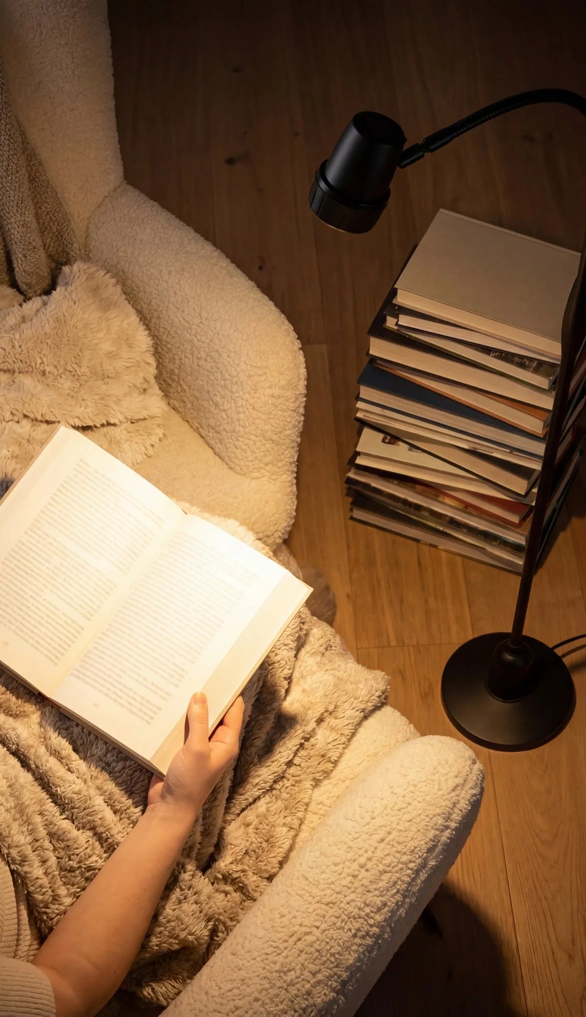 A woman reading, seen from above, with an HD Original Floor Light shining on her book