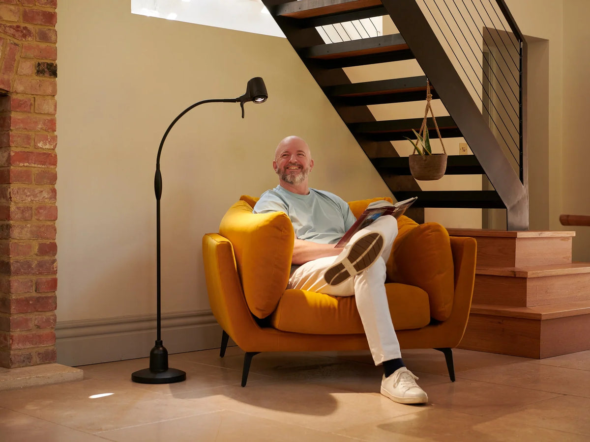 A man reading by a Serious Floor Light at the foot of the stairs