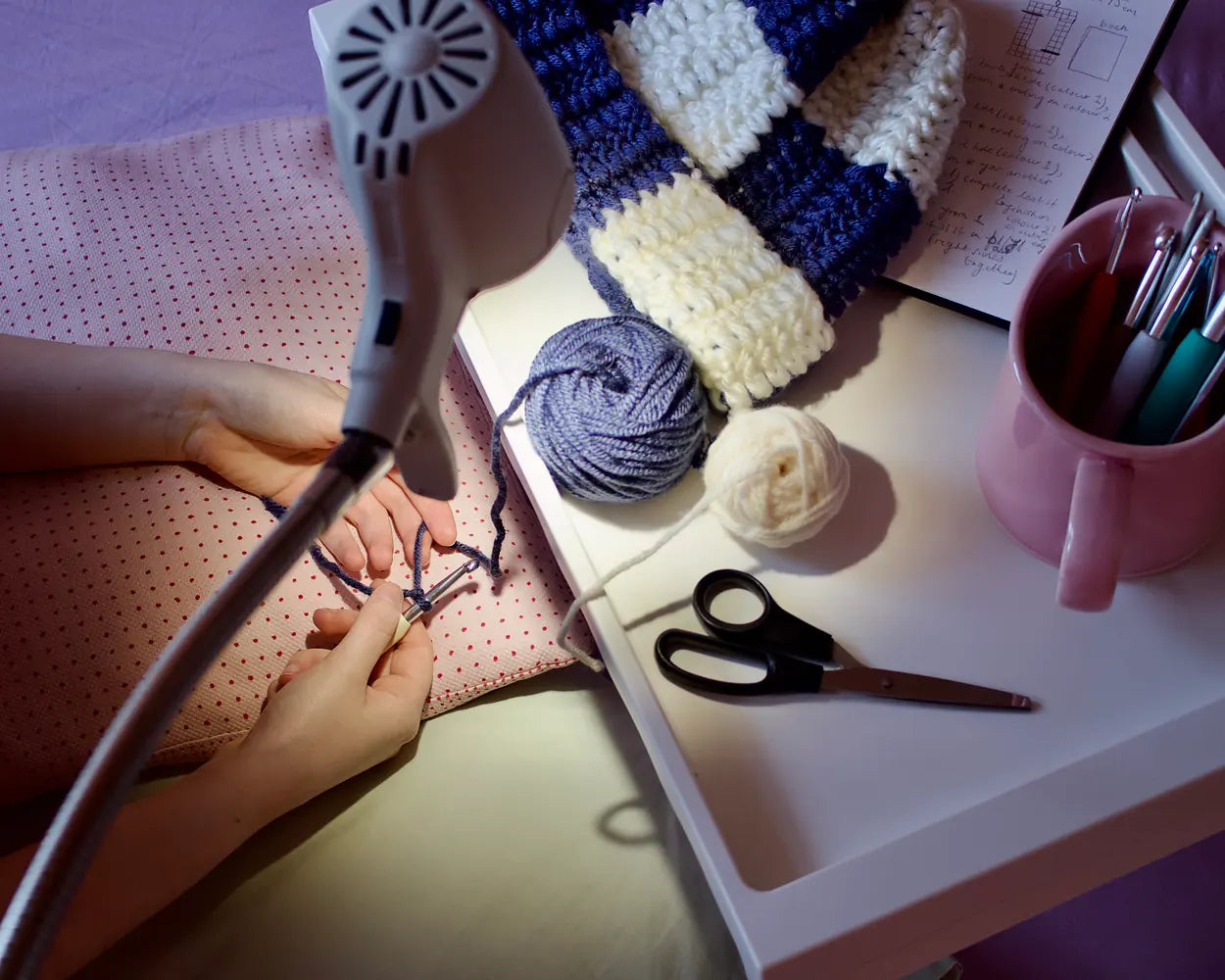 Hands crocheting with bright wool under a Serious light