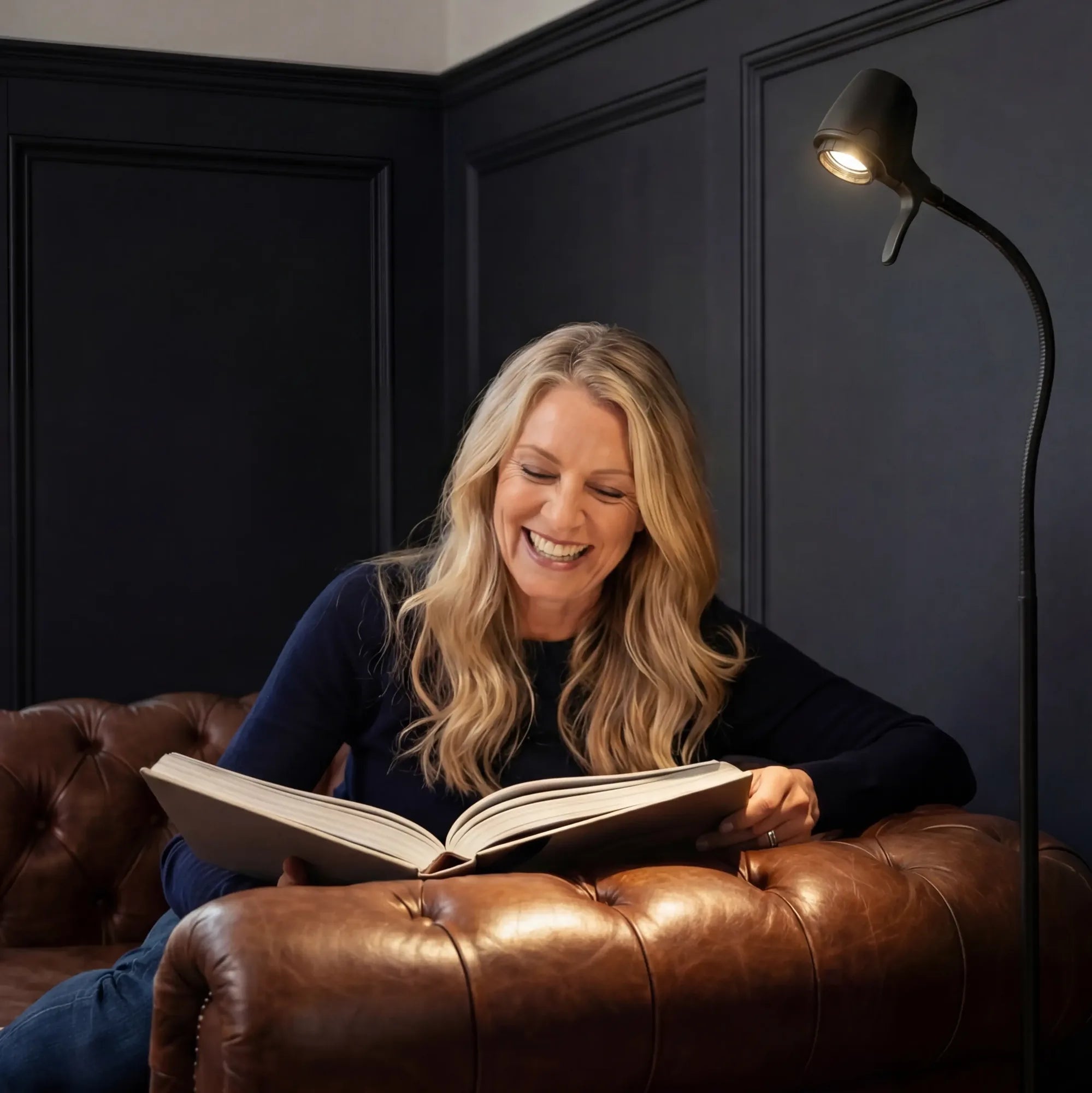 A woman enjoying a book in her armchair under a Serious light