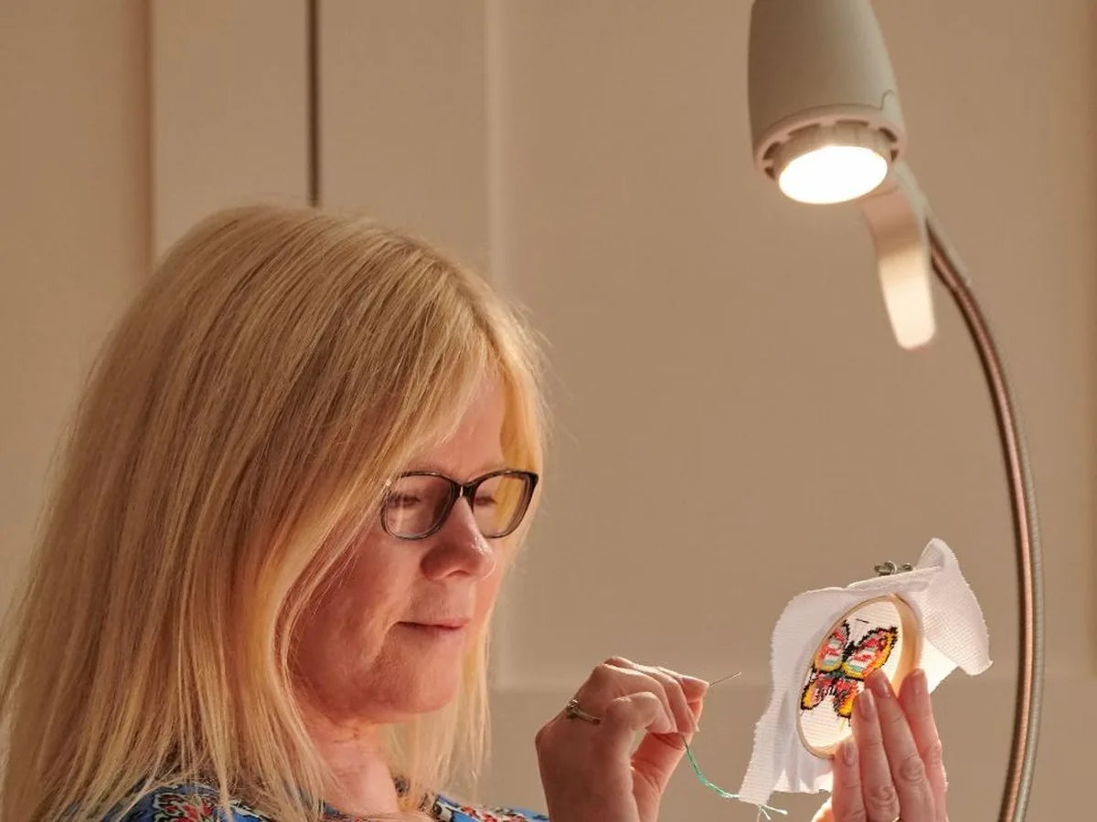 A woman seeing the colours in her embroidery under a Serious light