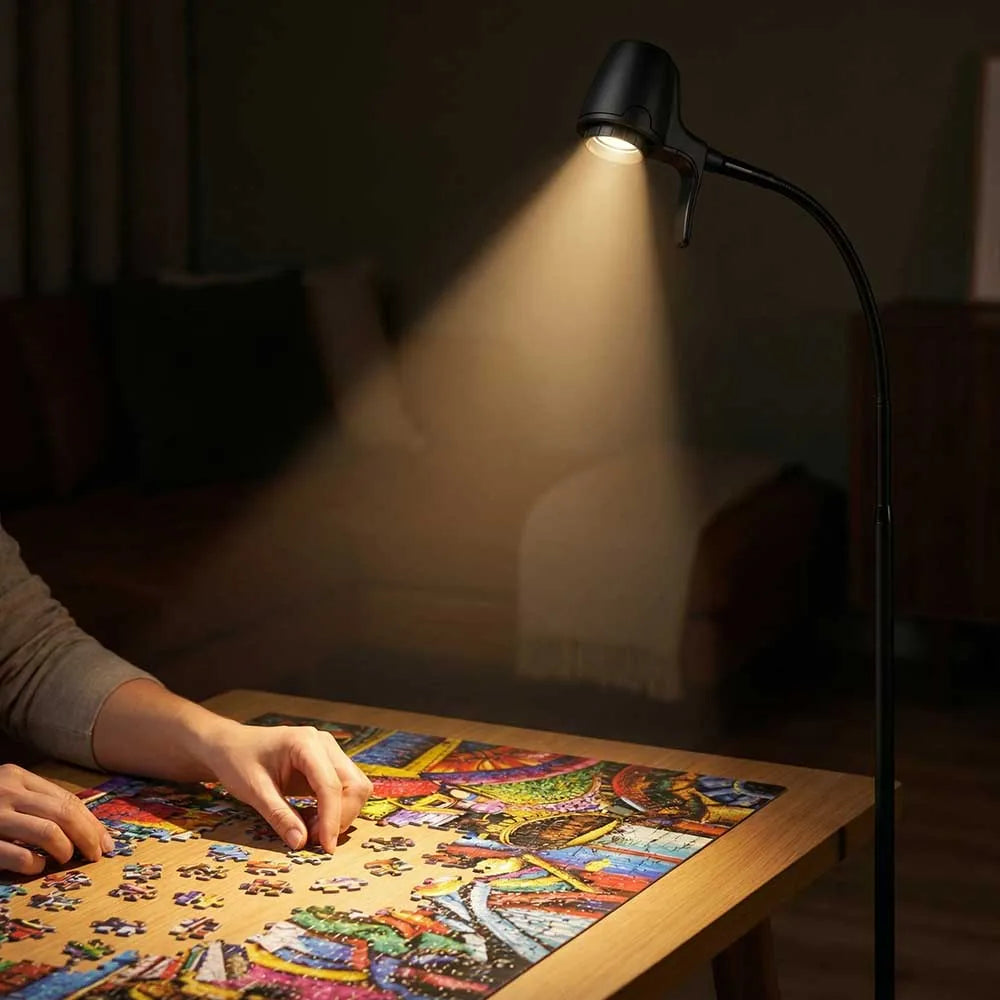 Hands fitting a colourful jigsaw on a wooden table, lit by a Serious Floor Light