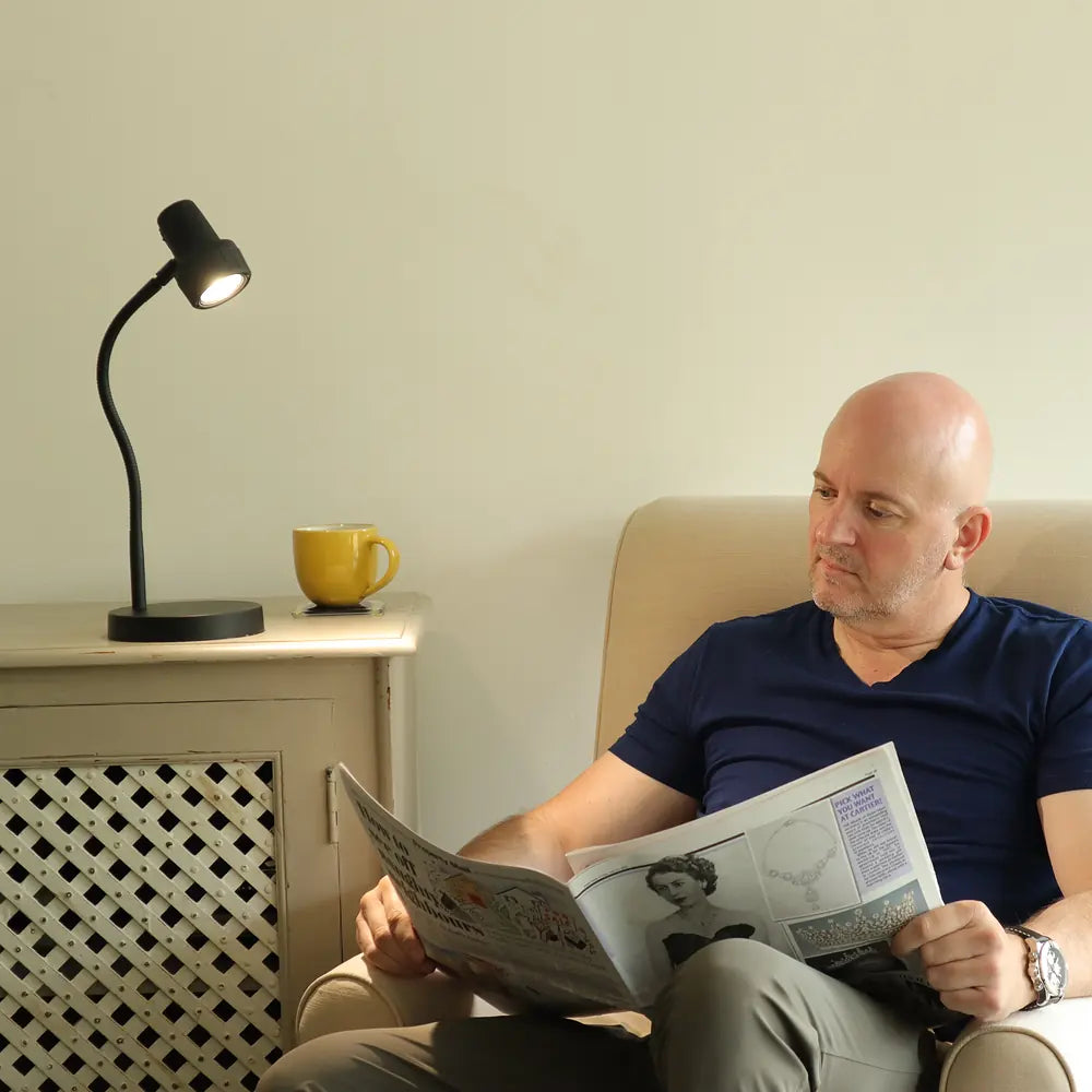 A man reading his newspaper in an armchair beside the HD Mini in Black