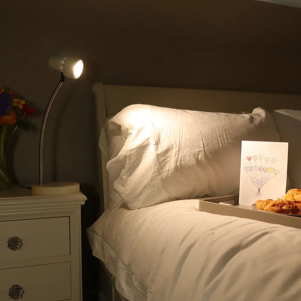The HD Mini in Heritage White lit on a bedside table at night